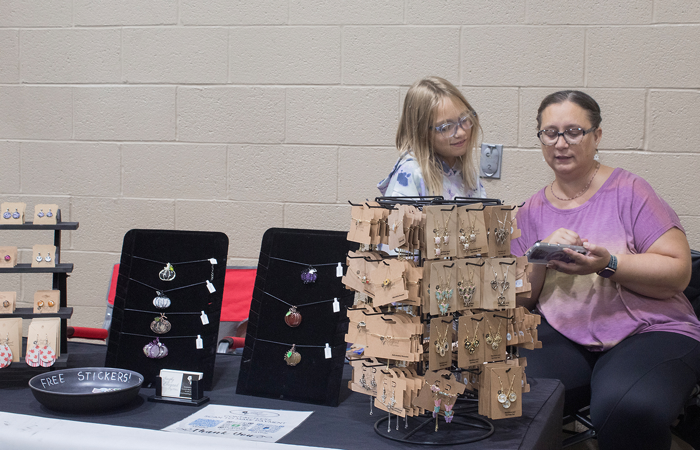 Adina Cook and her daughter, 10, are watching a video while waiting for customers. This is Adina's fifth year selling her jewelry at the Lebanon Valley Craft Show. (Kailey Killian)