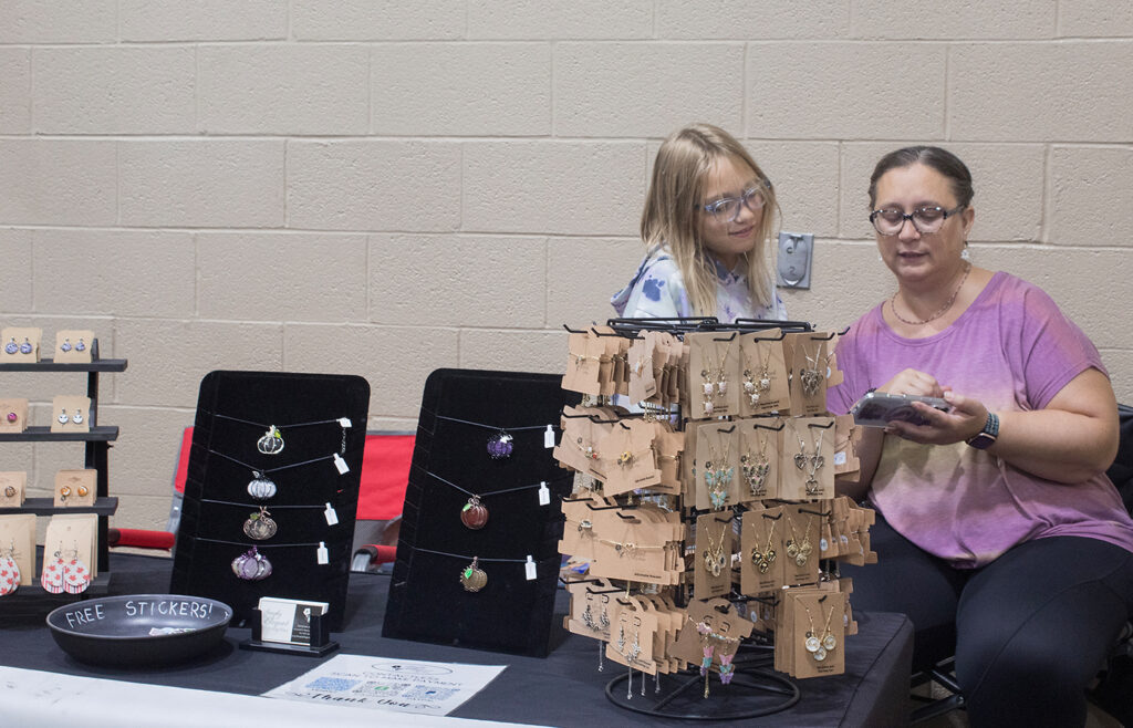 Adina Cook and her daughter, 10, are watching a video while waiting for customers. This is Adina's fifth year selling her jewelry at the Lebanon Valley Craft Show. (Kailey Killian)
